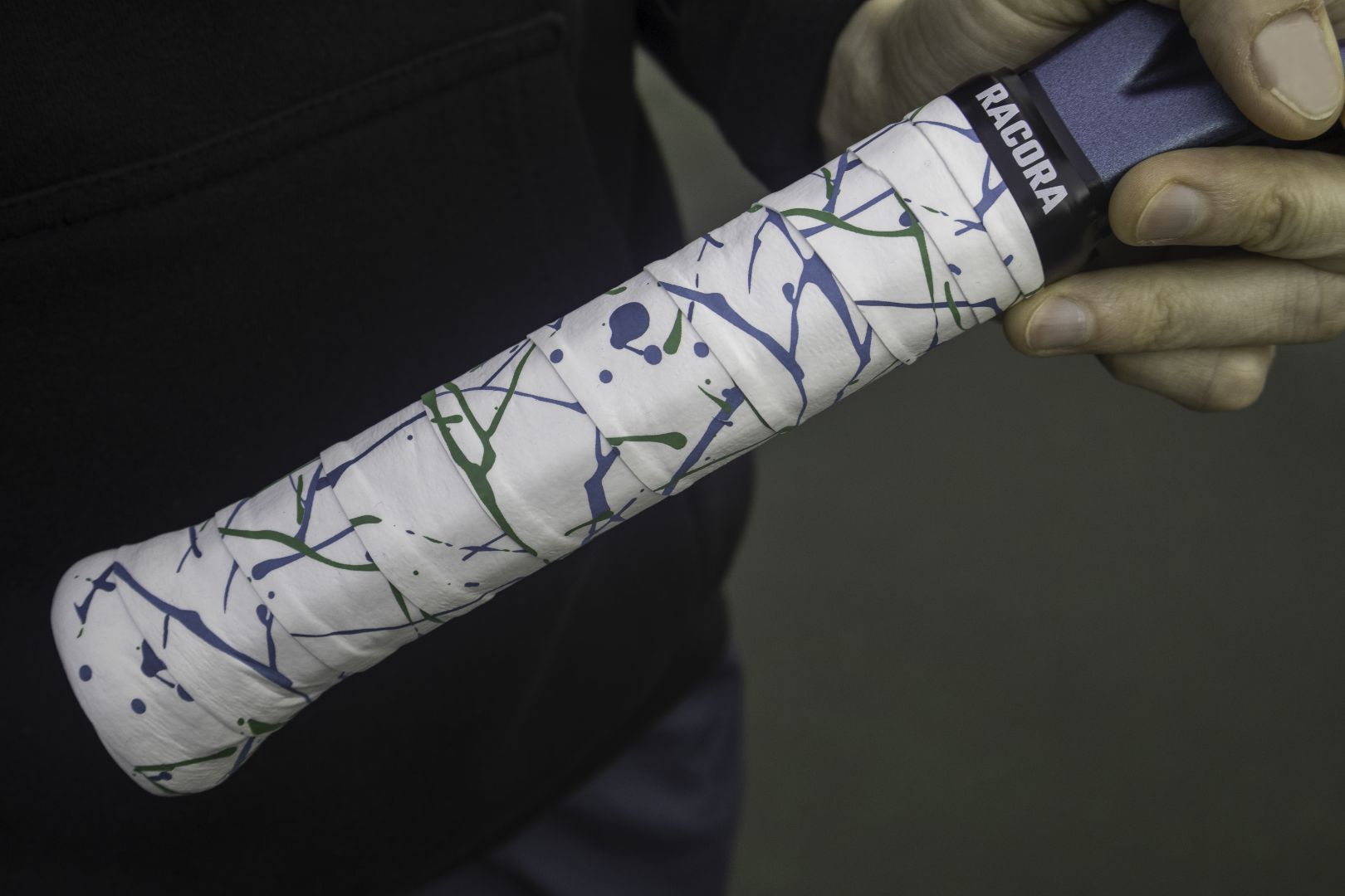 Racora Wild Drip tennis overgrip on tennis racket, held by tennis player