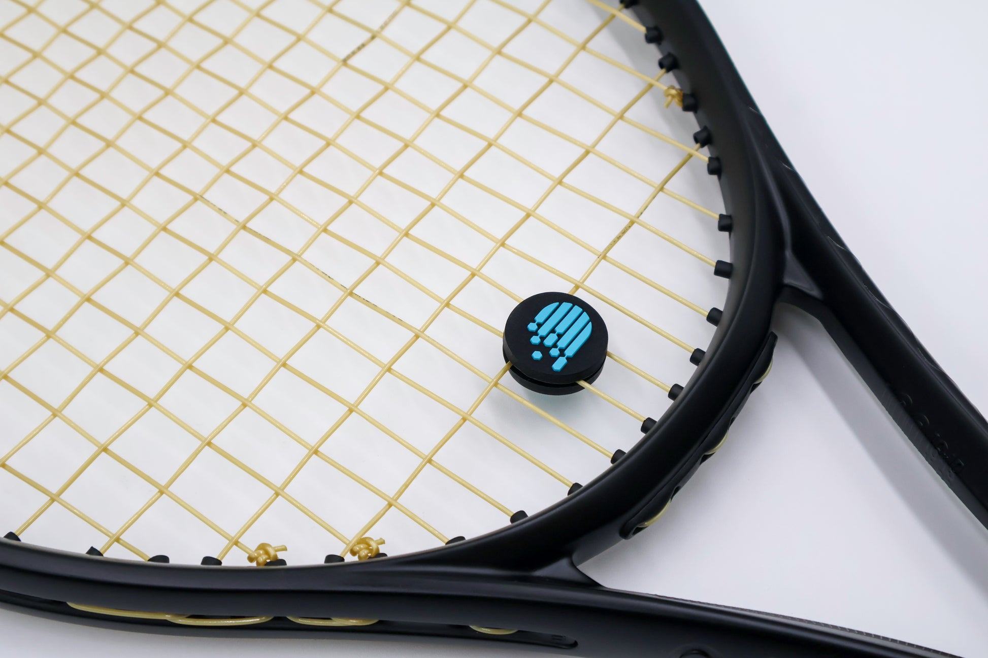 Racora black vibration dampener on tennis racket shown at an angle